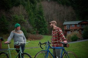 A man and woman smiling and talking while holding up their bikes in the mountains of North Carolina